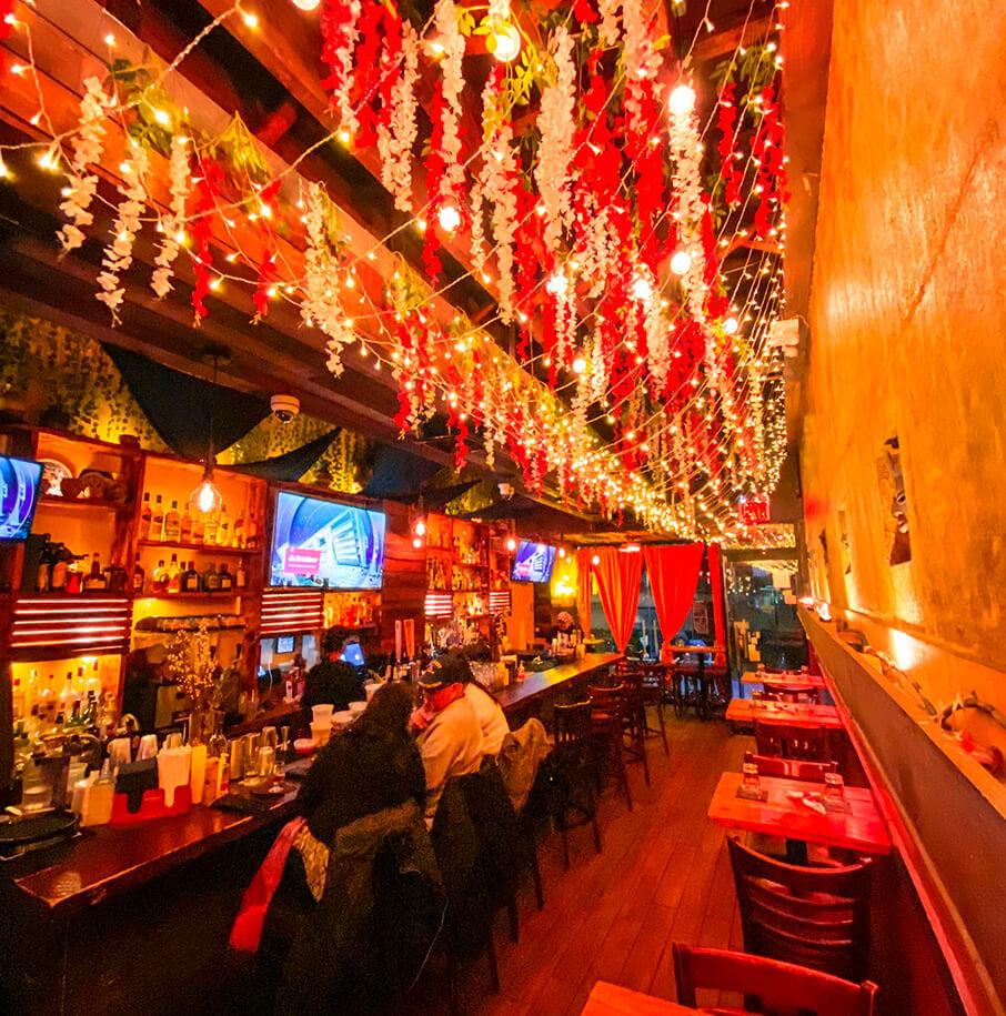 Lunera bar in Astoria, Queens at night under hanging flowers and string lights