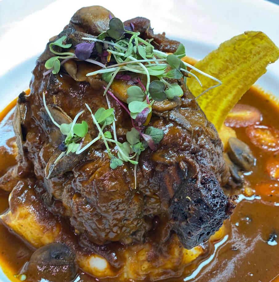 Slow-braised meat over mash with a fried plantain chip